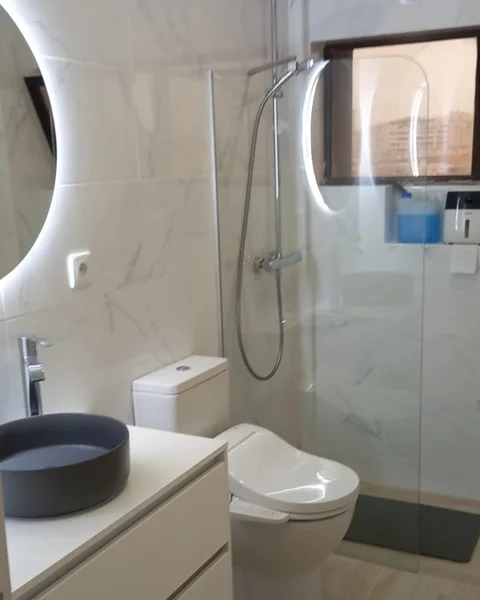Luxury bathroom remodel in Algarve with marble walls, black frame shower screen and natural light