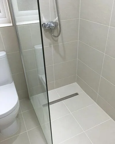 Walk-in shower renovation in Algarve with grey tiles, glass screen and linear drain