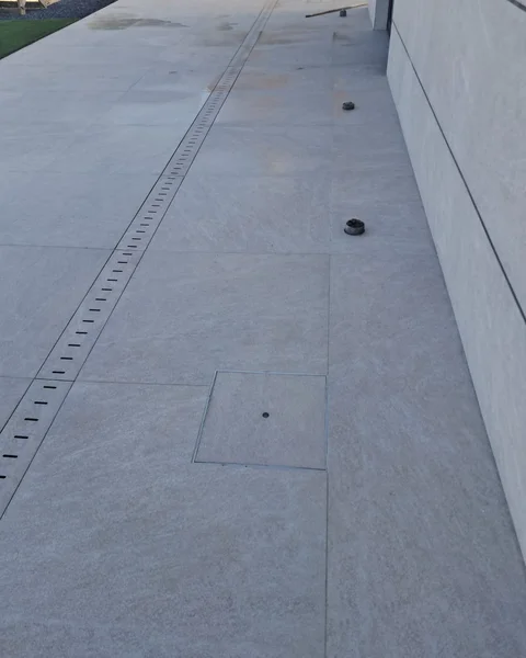 Professional outdoor tiling work in Algarve with grey stone tiles, drainage system and modern finish